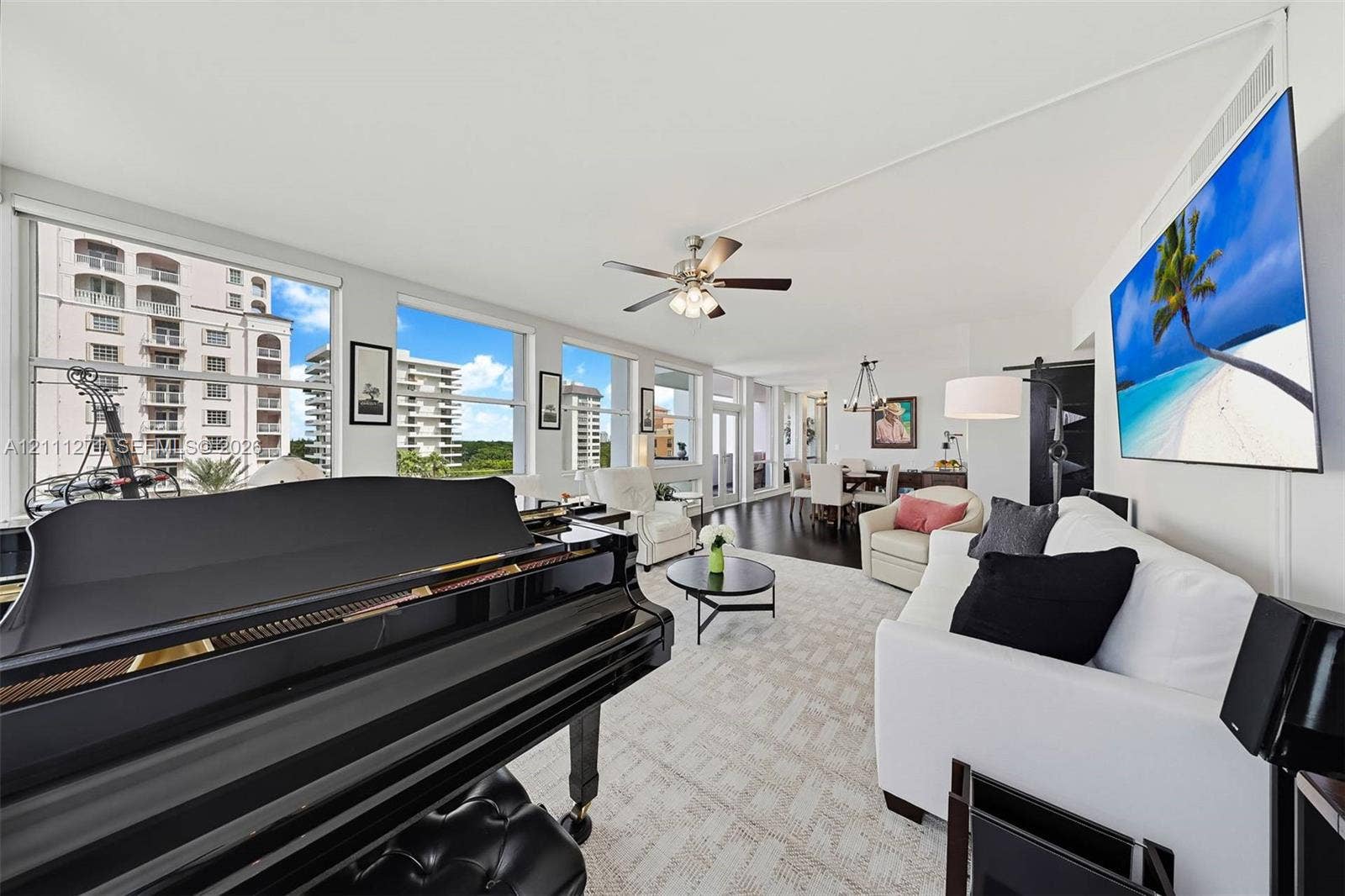 Open-concept interior featuring oversized windows, wood-finish flooring, and a ceiling fan with integrated lighting