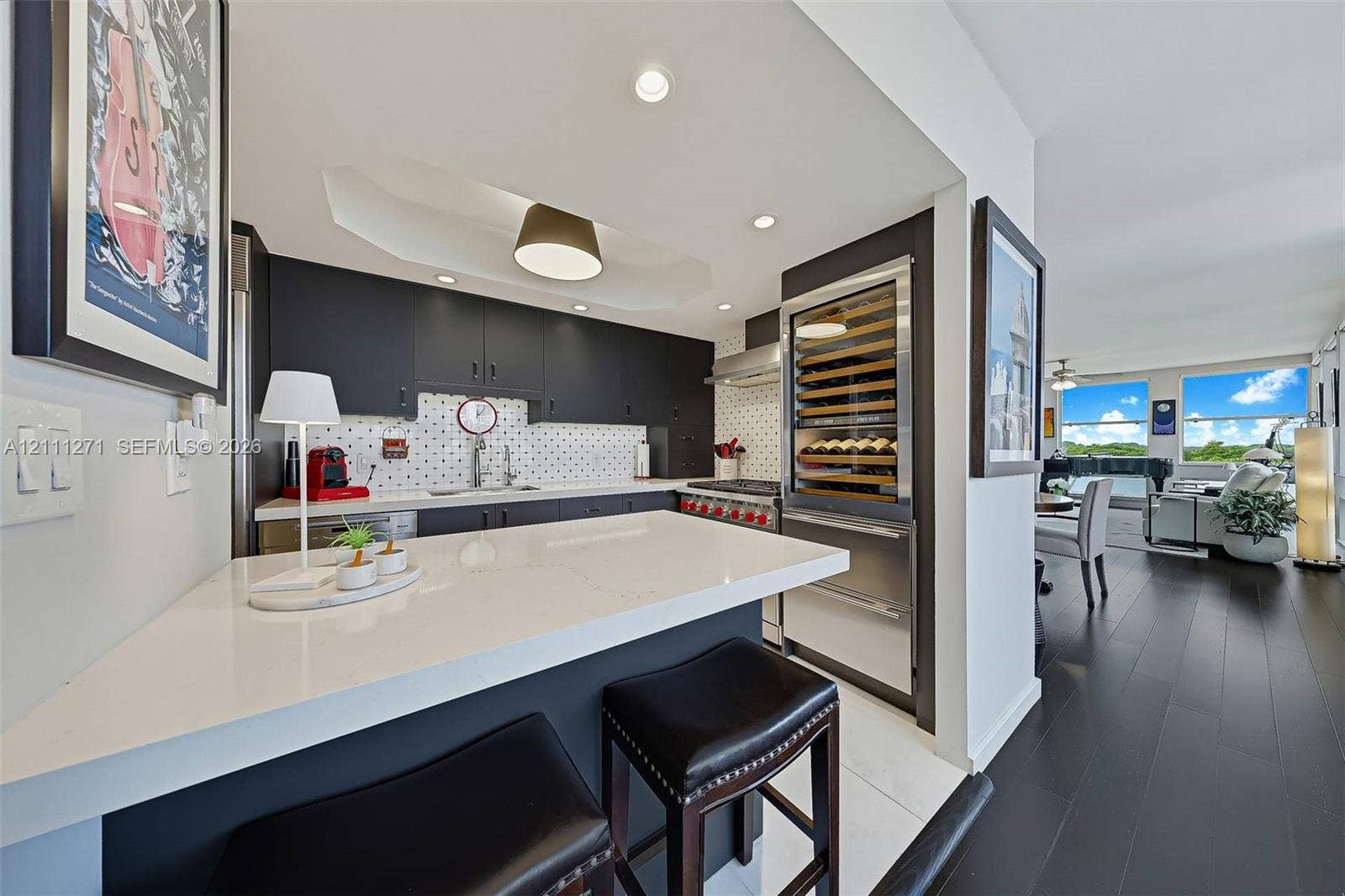 Kitchen featuring dark cabinetry, solid-surface breakfast bar, mosaic tile backsplash, stainless steel range, and built-in wine refrigeration