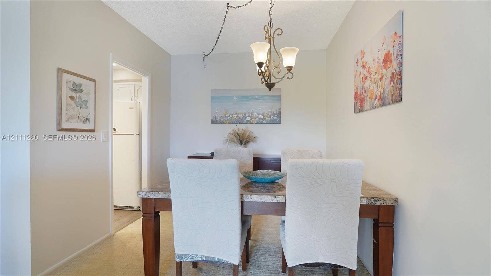 400 N Riverside Drive, #305, Pompano Beach, FL 33062 Dining area featuring a three-arm chandelier with frosted glass shades and neutral wall finishes