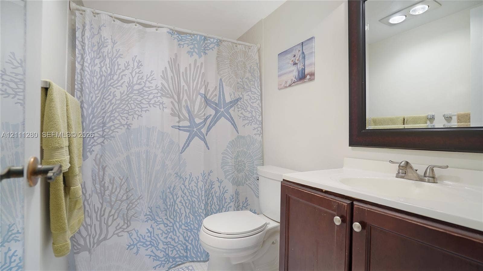 400 N Riverside Drive, #305, Pompano Beach, FL 33062 Bathroom featuring a dark wood-finish vanity, integrated sink basin with a dual-handle faucet, and a wall-mounted mirror with a matching dark wood frame