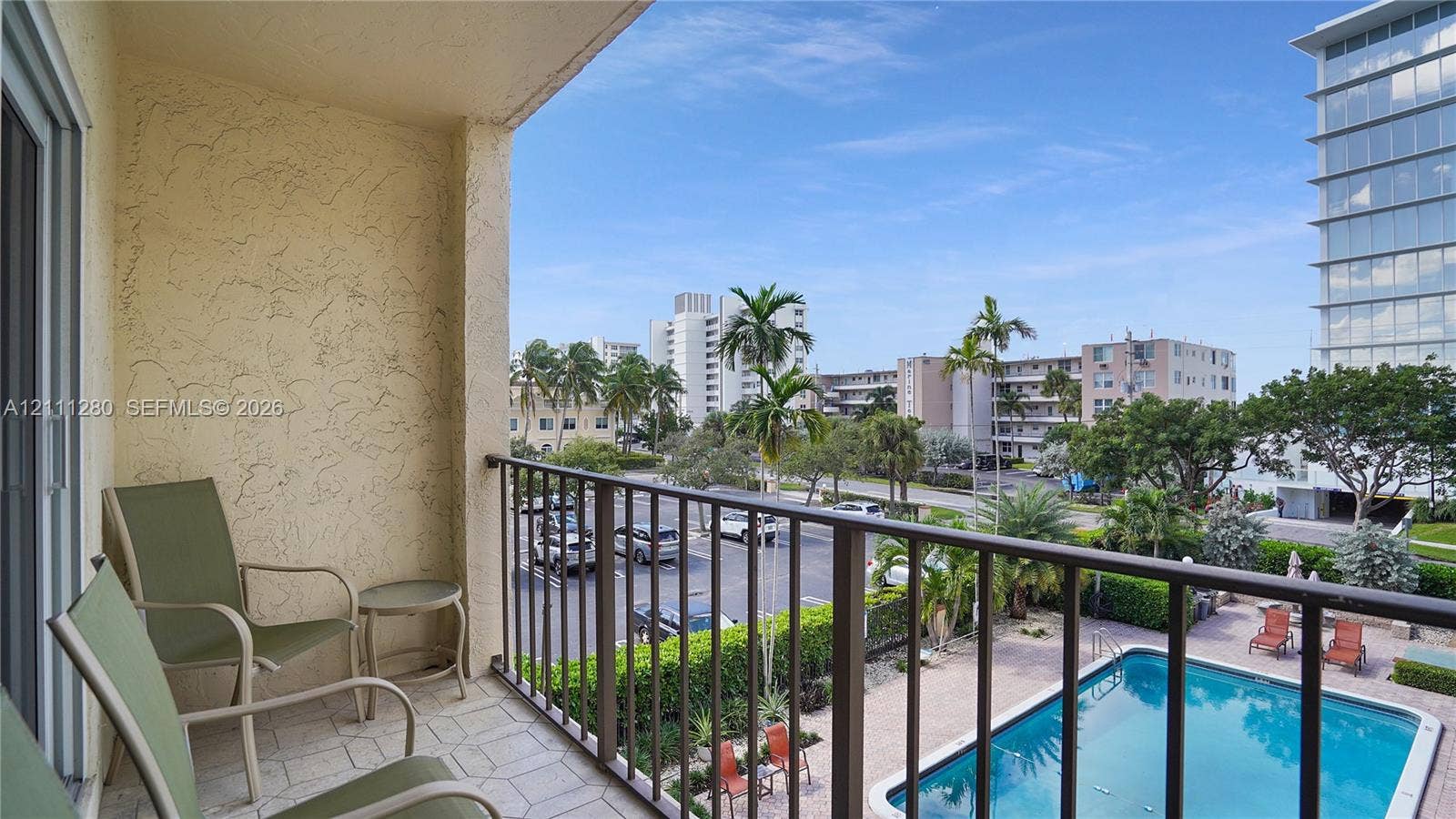 400 N Riverside Drive, #305, Pompano Beach, FL 33062 Covered balcony featuring tile flooring and metal railings, overlooking an in-ground swimming pool and landscaped grounds