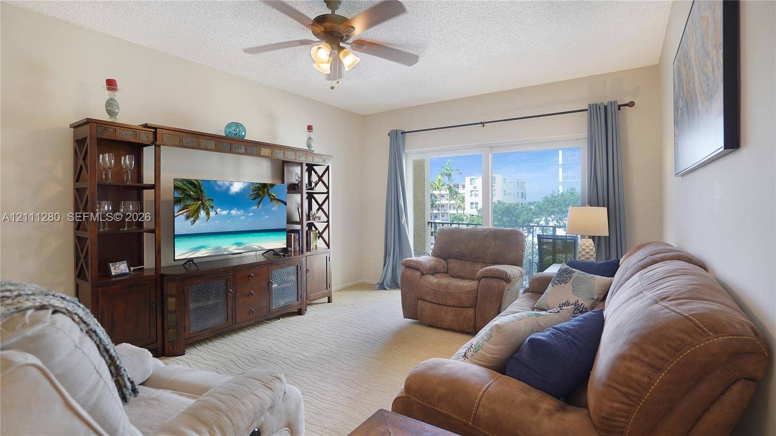 400 N Riverside Drive, #305, Pompano Beach, FL 33062 Living space featuring a ceiling fan with integrated lighting and sliding glass doors providing external access