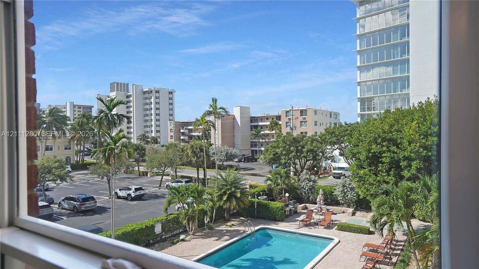 400 N Riverside Drive, #305, Pompano Beach, FL 33062 Outdoor swimming pool with masonry paver decking, surrounding manicured landscaping, and mature palm trees