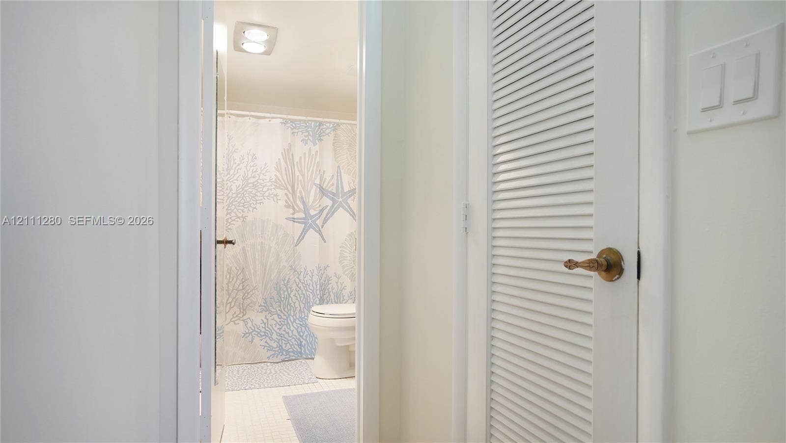 400 N Riverside Drive, #305, Pompano Beach, FL 33062 White louvered door featuring brass hardware, square-edged white door casing, and white light switch plate