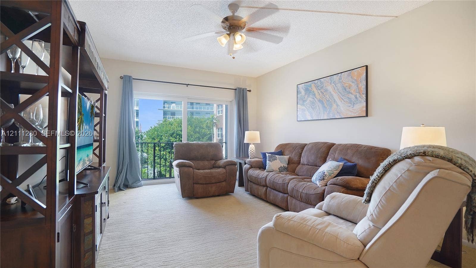 400 N Riverside Drive, #305, Pompano Beach, FL 33062 Living area featuring sliding glass doors, a ceiling fan with integrated lighting, and a metal-railing balcony