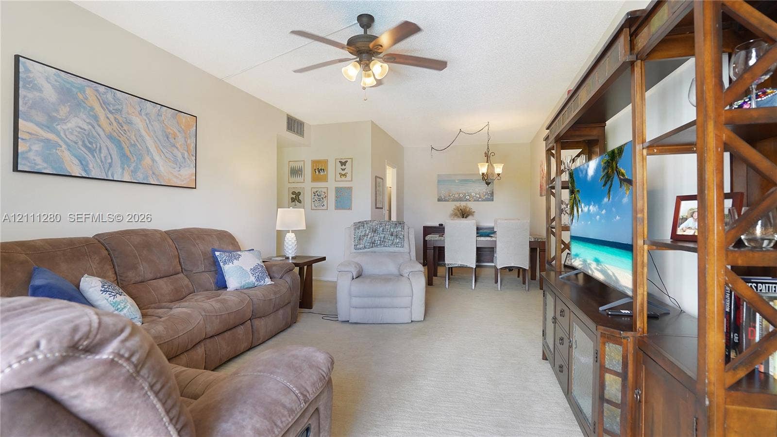400 N Riverside Drive, #305, Pompano Beach, FL 33062 Living area featuring neutral carpeting, a ceiling fan with integrated lighting, and a multi-arm overhead chandelier