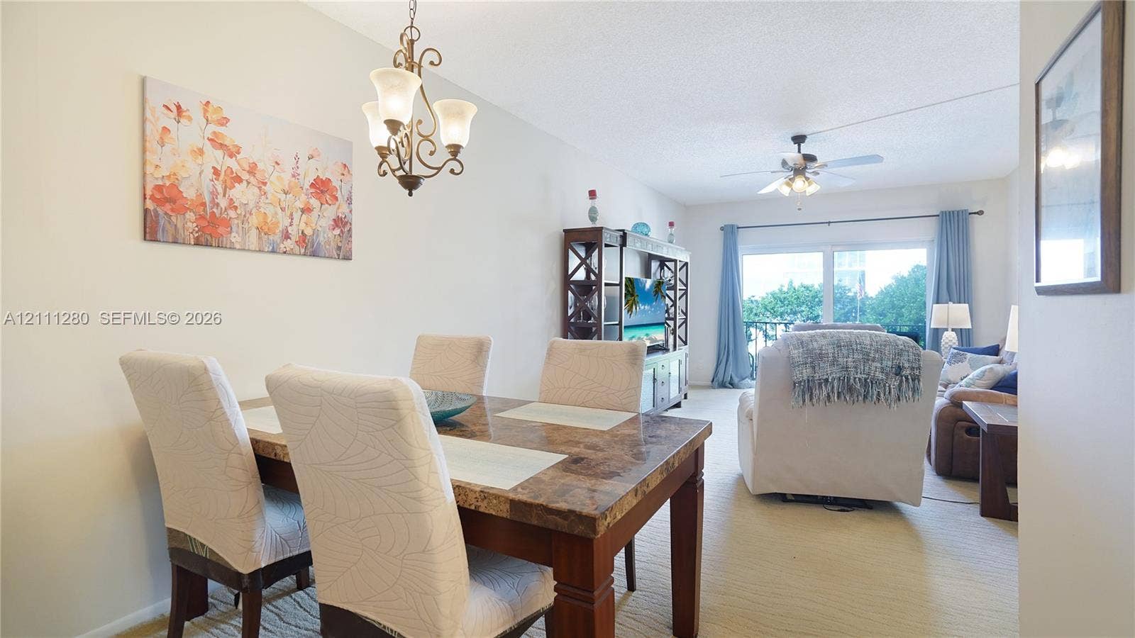 400 N Riverside Drive, #305, Pompano Beach, FL 33062 Open-concept interior featuring vaulted ceilings, a decorative wrought-iron chandelier, ceiling fan with integrated lighting, and sliding glass doors