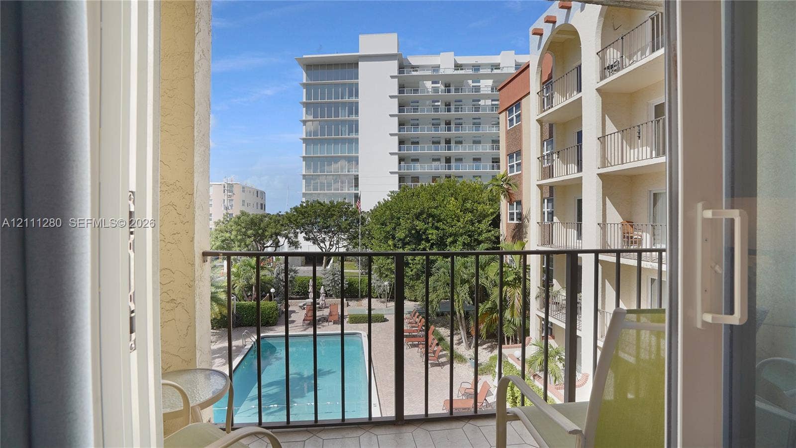 400 N Riverside Drive, #305, Pompano Beach, FL 33062 Balcony with metal railing overlooking an in-ground swimming pool and landscaped grounds