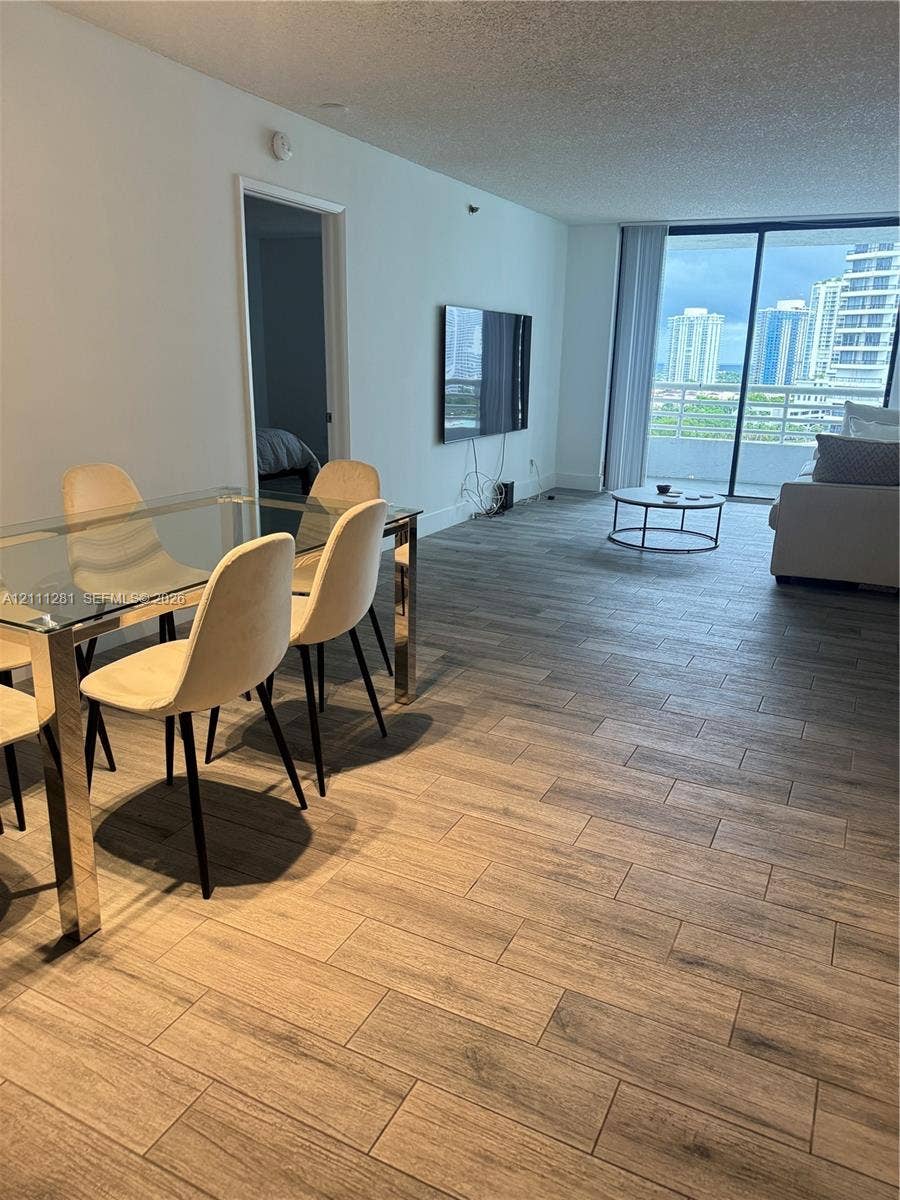 Open-concept interior featuring porcelain-finish flooring, floor-to-ceiling glass sliding doors, and a private balcony