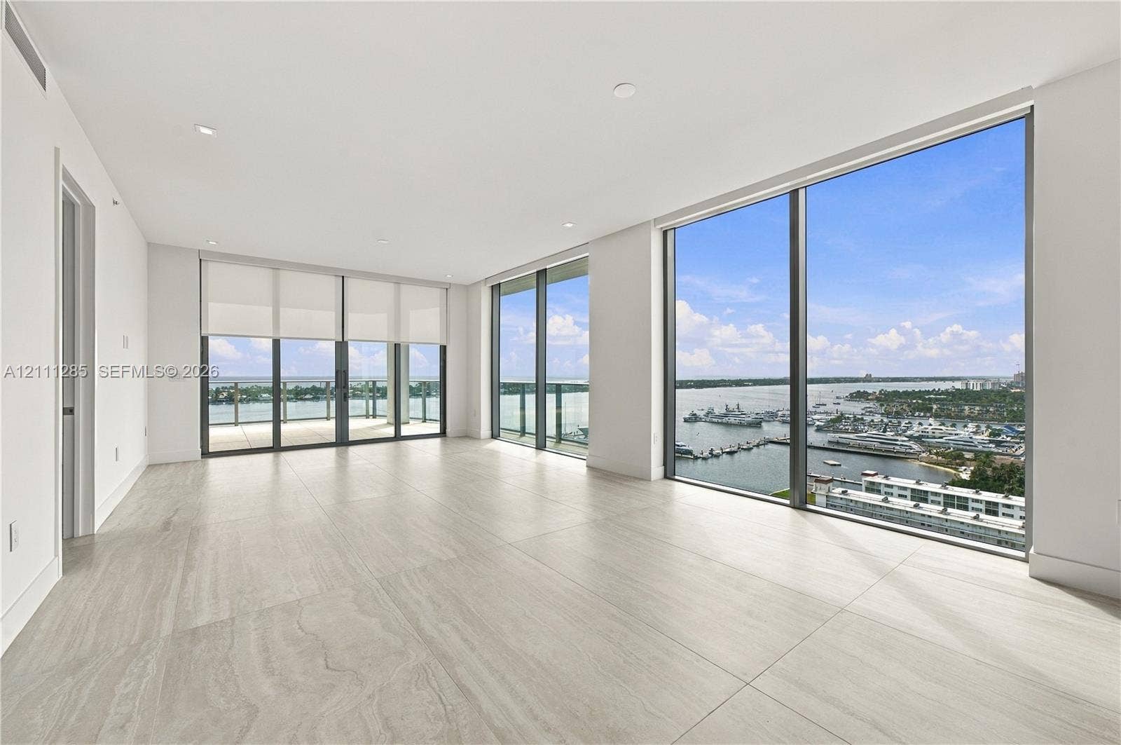Expansive living area featuring floor-to-ceiling windows, large-format tile flooring, recessed lighting, and a private balcony