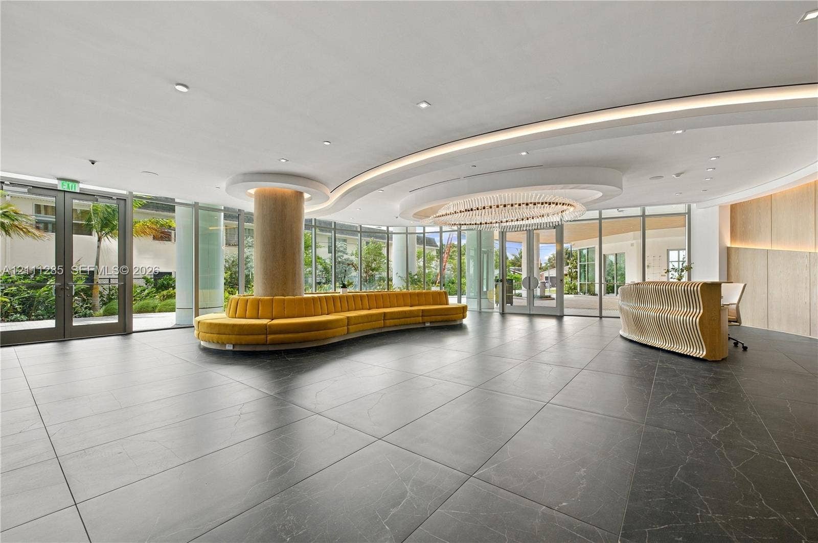 Lobby featuring large-format dark stone flooring, floor-to-ceiling glass walls, recessed cove lighting, and a circular chandelier