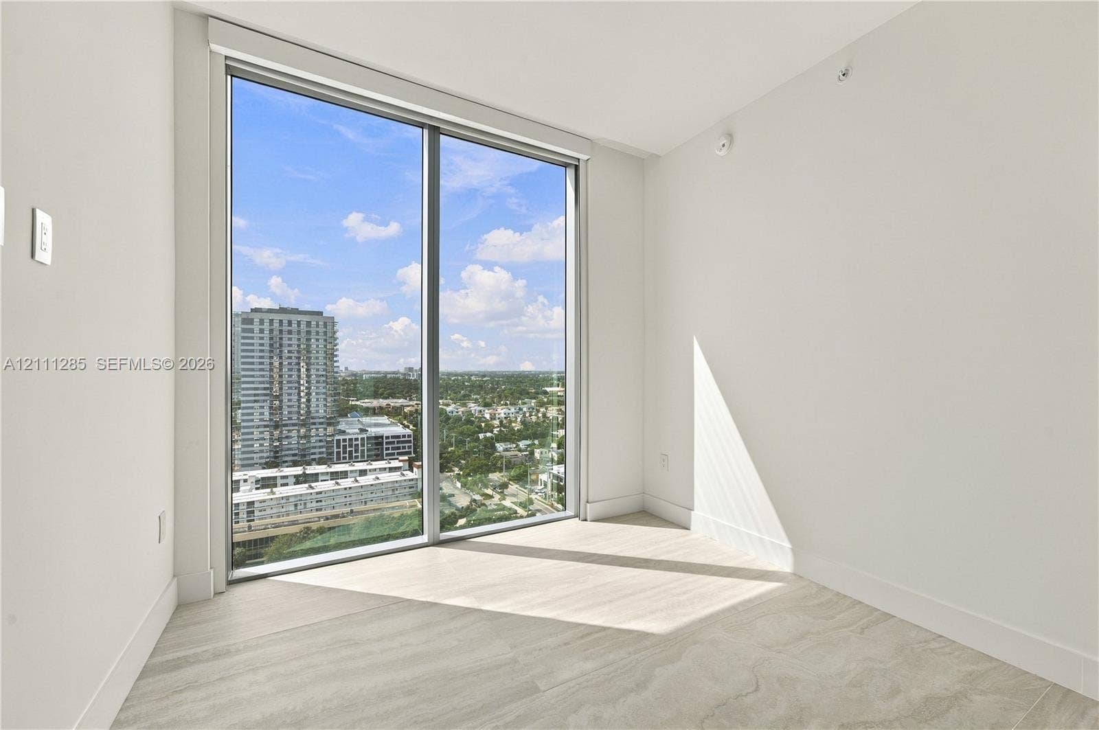 Floor-to-ceiling windows, neutral interior walls, and light-toned tile flooring