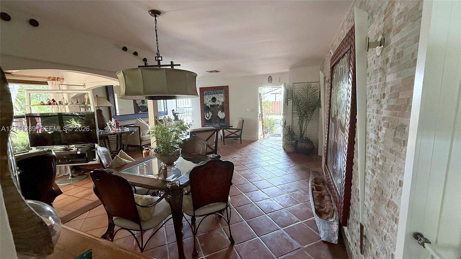 Terra cotta tile flooring, stacked stone wall accent, and a drum-style pendant light fixture