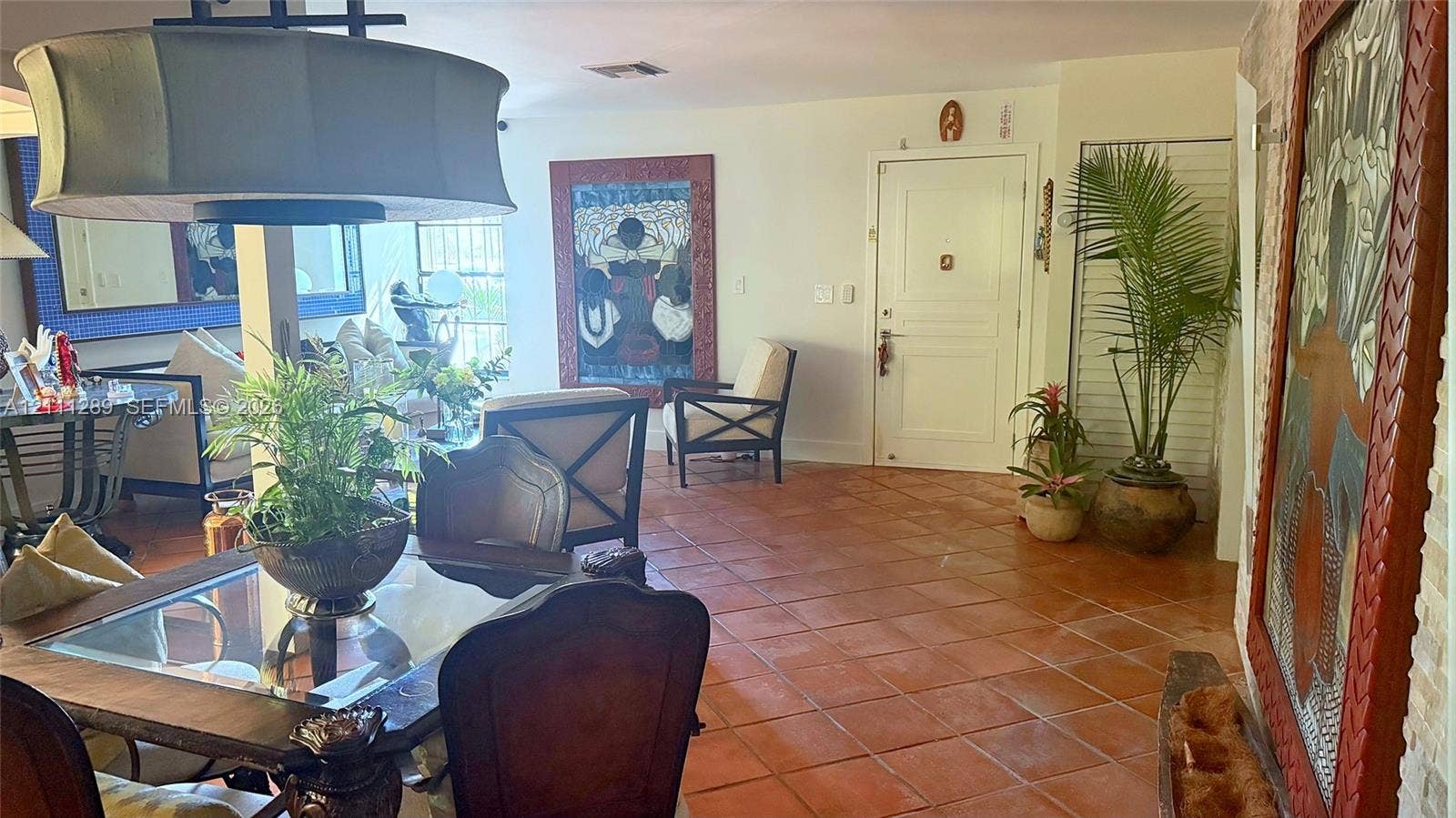 Terra-cotta tile flooring, oversized drum pendant lighting, and solid-core six-panel entry door