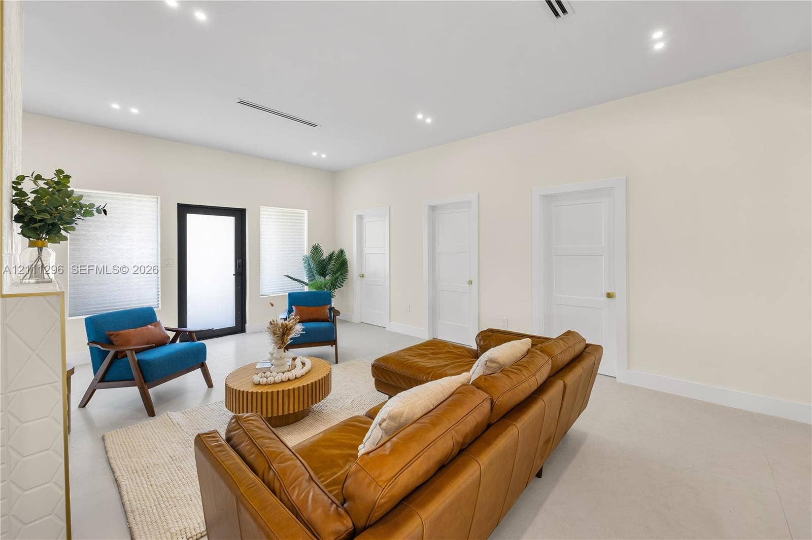 Neutral-toned interior featuring smooth-finish flooring, recessed ceiling lighting, three paneled interior doors, and a black-framed glass-panel entry door
