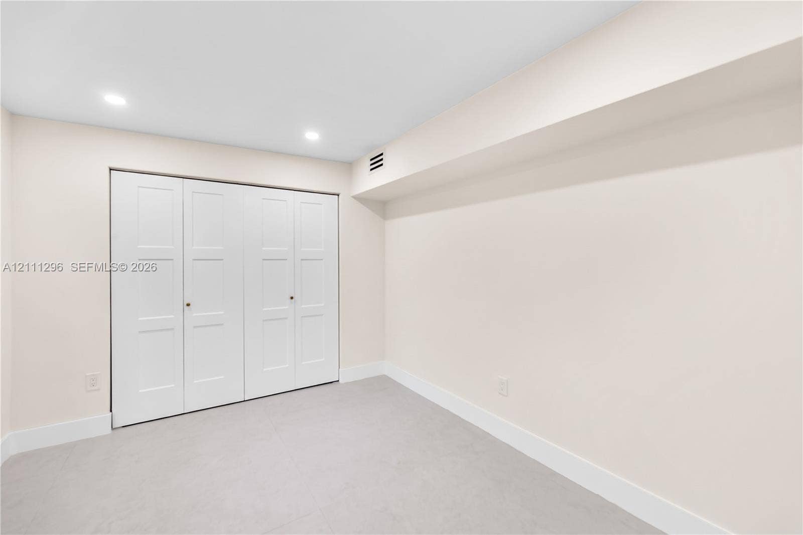 Neutral-toned interior space featuring recessed ceiling lighting and a four-panel bi-fold closet