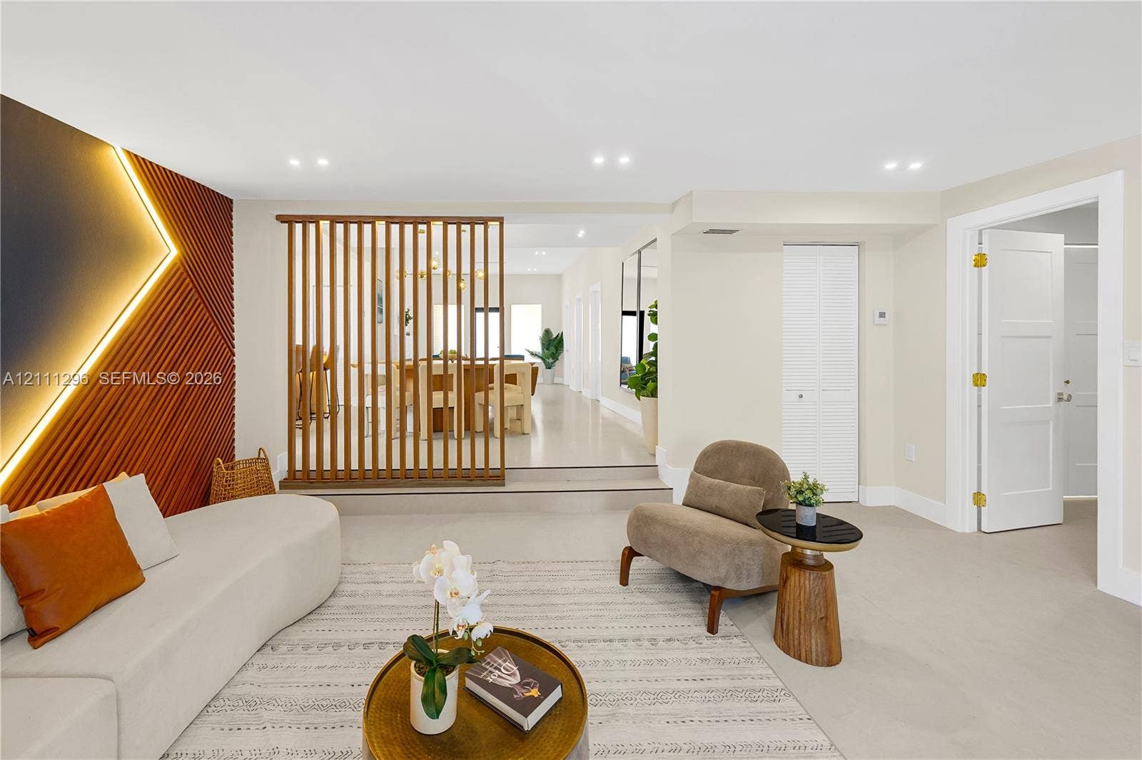 Living area featuring a vertical-slat wood room divider, textured accent wall with recessed lighting, smooth-finish flooring, and recessed ceiling lights