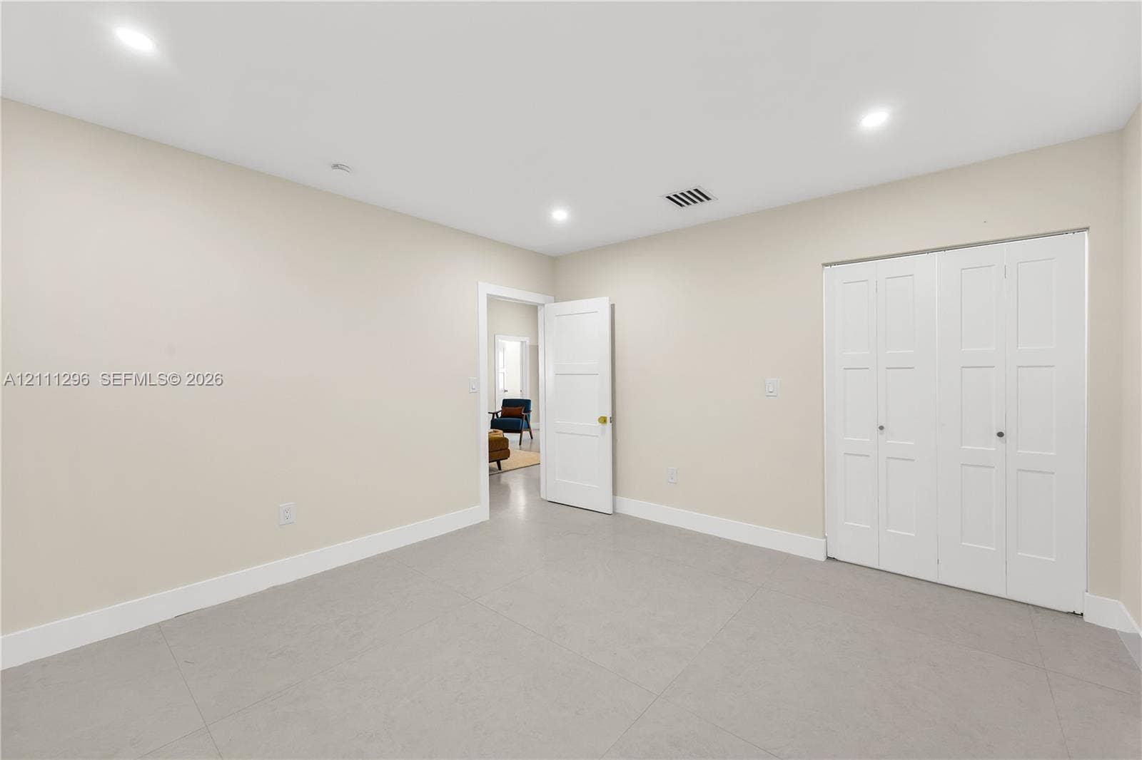 Neutral-toned room featuring recessed lighting, smooth-finish flooring, and a multi-panel door closet with white finish