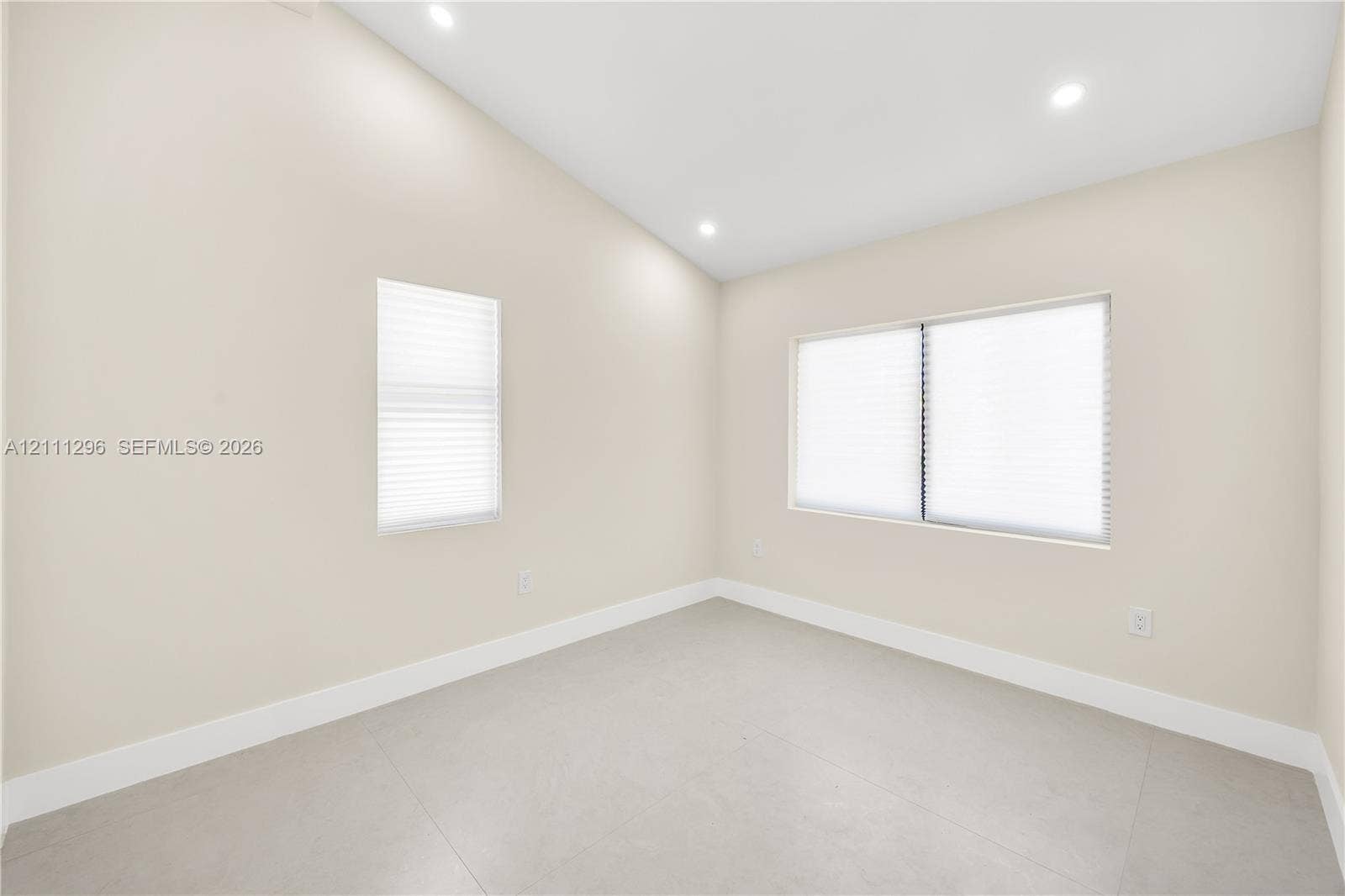 Vaulted ceilings featuring recessed lighting, large-format neutral tile flooring, and multiple windows with integrated blinds
