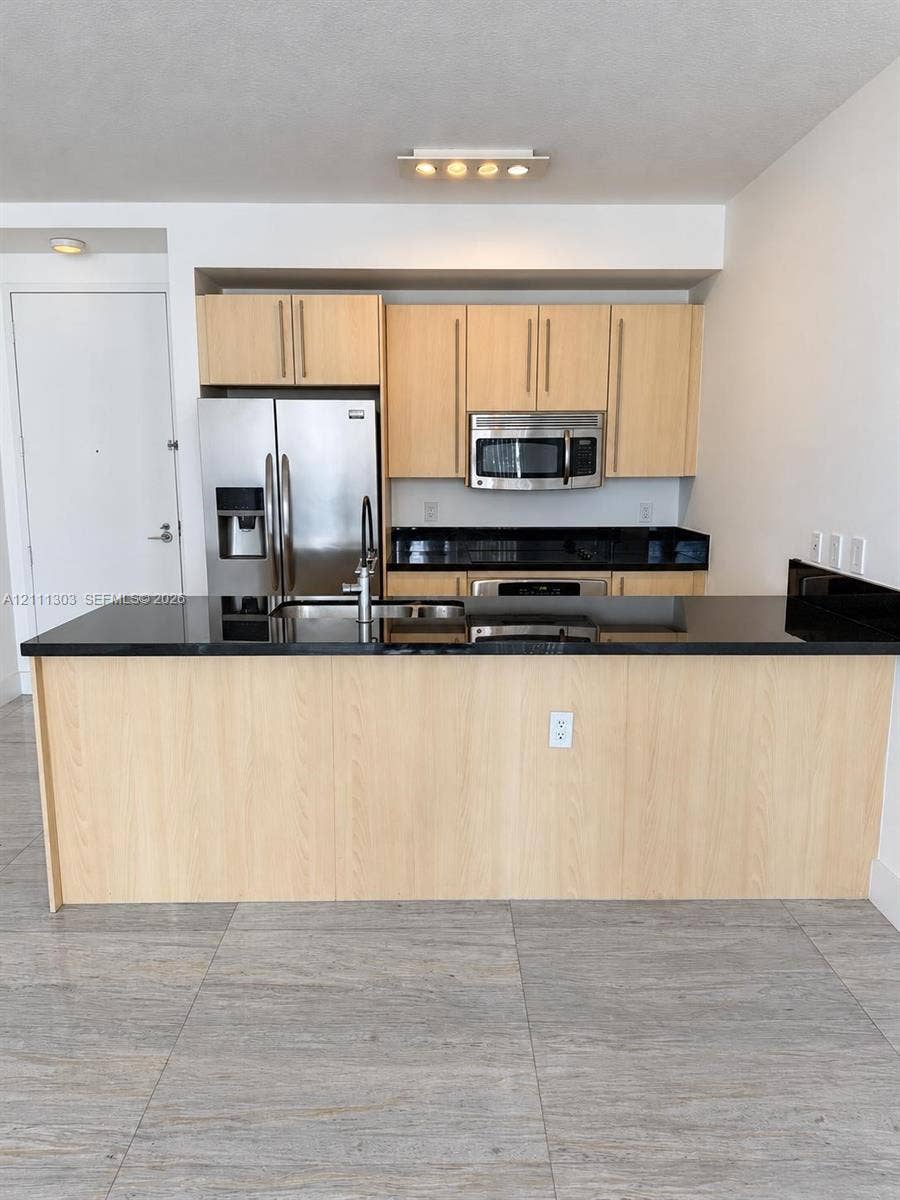 1111 SW 1st Avenue, #2324-N, Miami, Miami, FL 33130 Kitchen featuring a central island with a solid surface countertop, light wood-finish cabinetry, stainless steel appliances, and large-format tile flooring