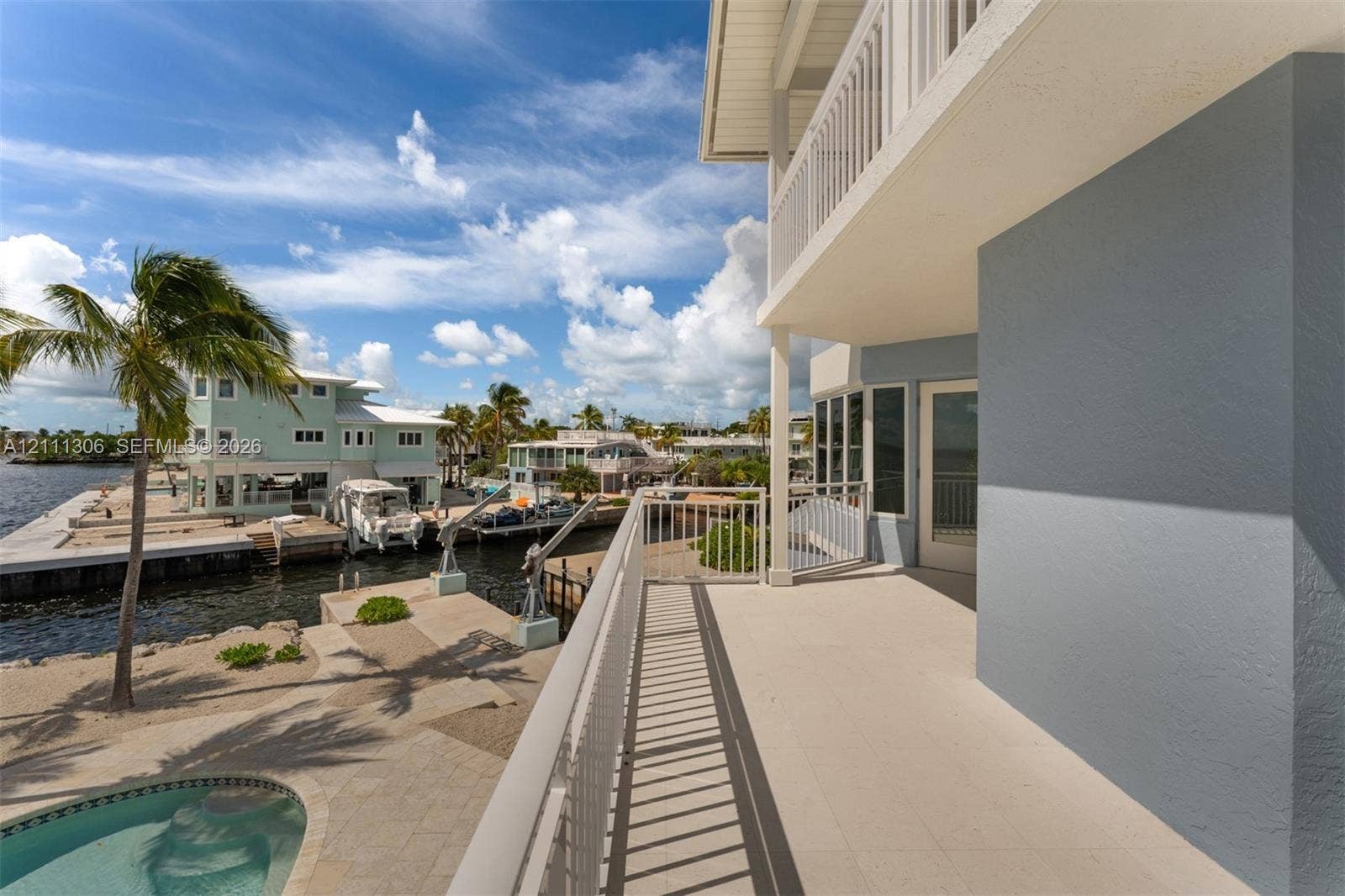 Covered balcony with white metal railings, light-toned paved decking, and direct exterior access