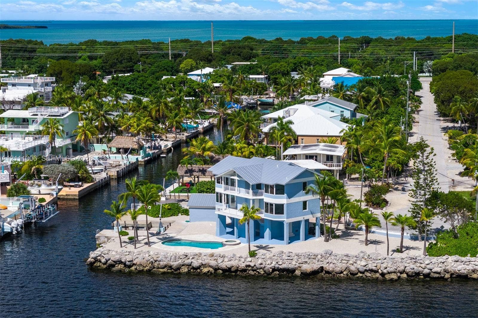 Waterfront property featuring a canal-side location, multi-story elevated structure with a metal roof, swimming pool, and stone bulkhead