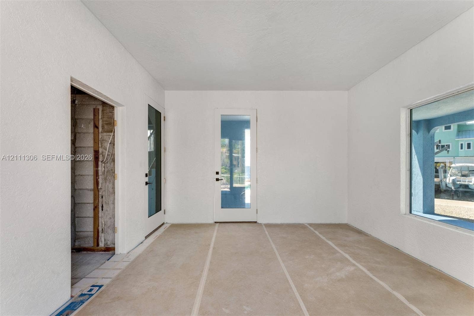 Interior space featuring smooth-finish white walls, a single-lite glass entry door, a dual-pane glass door, and a large picture window