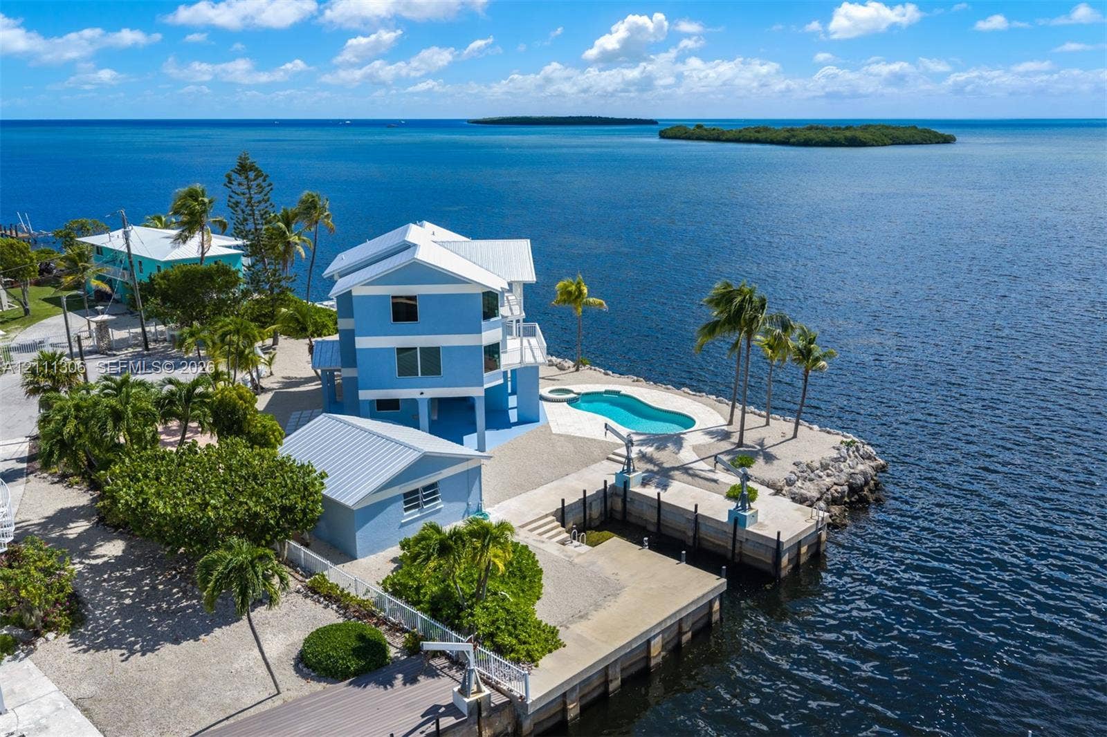Waterfront residence featuring a metal roof, private swimming pool, concrete dock, and multi-level structure