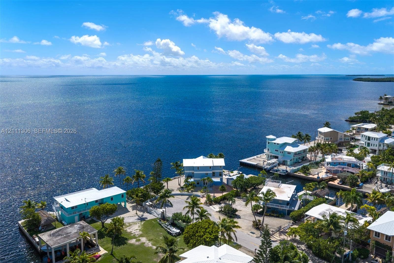 Waterfront coastal property featuring direct ocean access, multi-level structures, established palm trees, and paved driveways