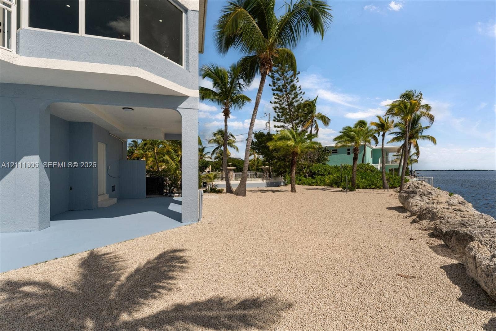 Waterfront exterior featuring a covered patio, pebble-surfaced ground, and natural stone seawall