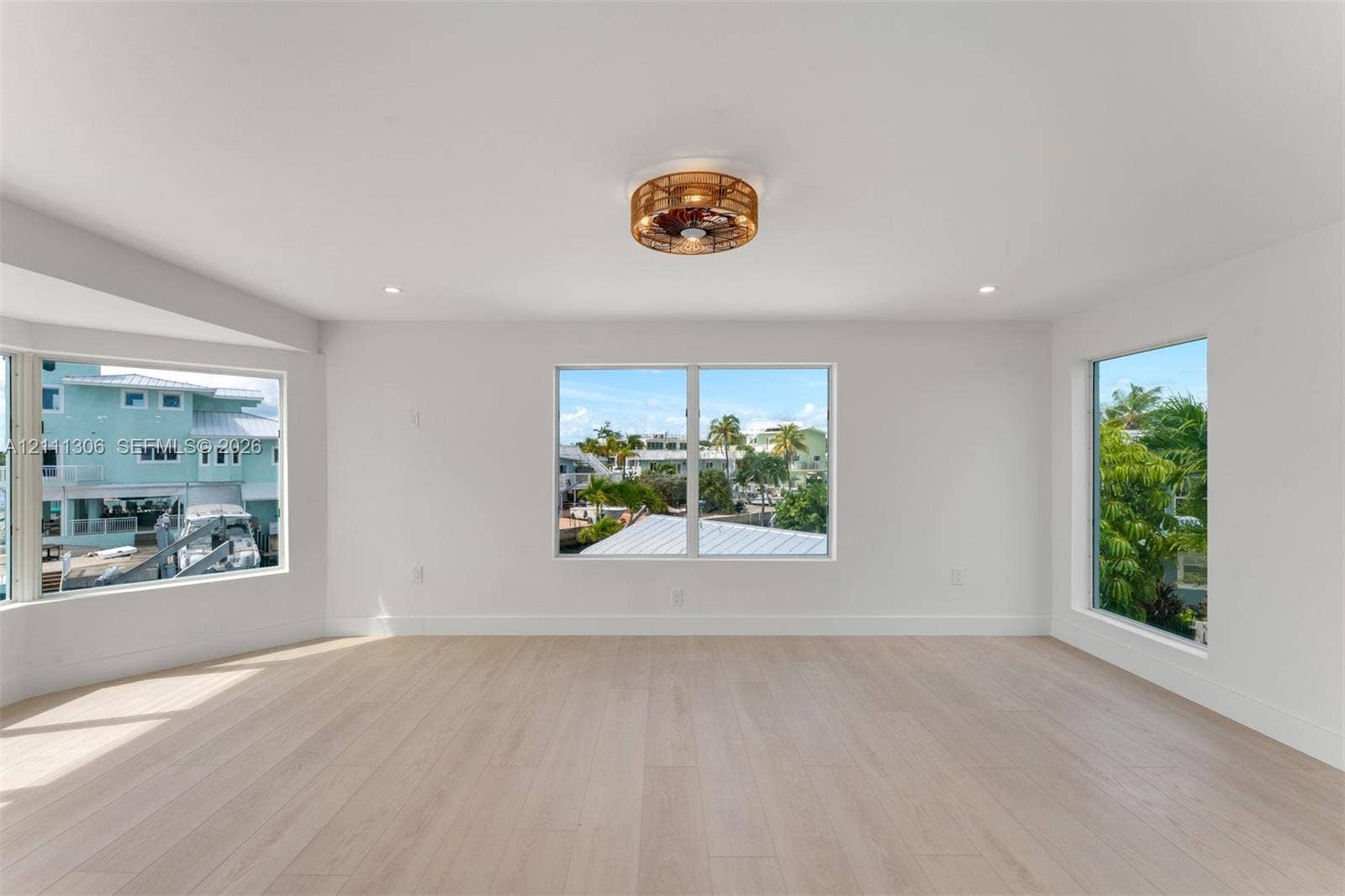 Light-filled room featuring wood-finish flooring, recessed lighting, and a circular wicker-style ceiling fixture
