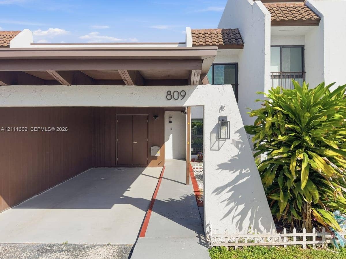 6518 Kendale Lakes Drive, #809, Miami, Miami, FL 33183 Exterior facade featuring a covered carport, built-in storage, concrete walkway, and stucco finish with tile roof accents