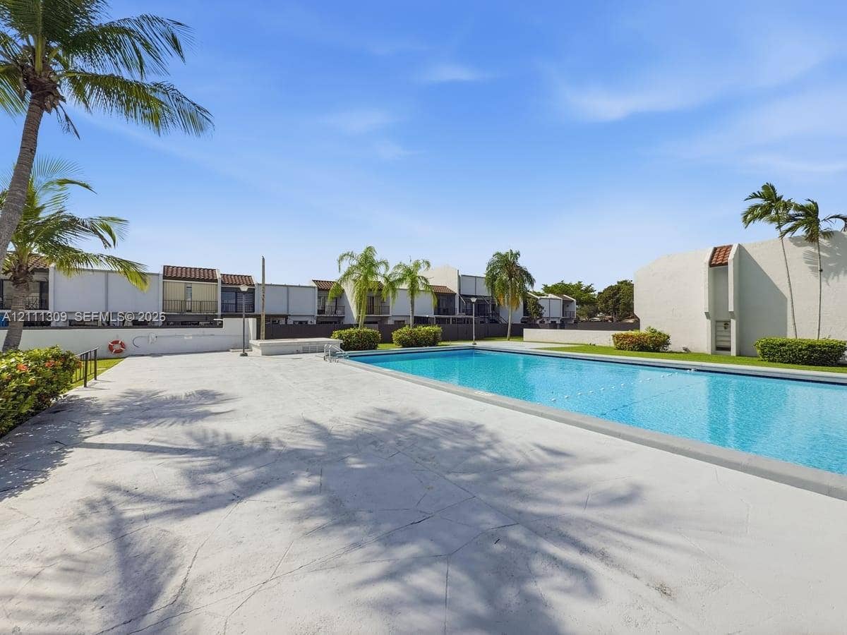 6518 Kendale Lakes Drive, #809, Miami, Miami, FL 33183 Rectangular swimming pool featuring a concrete deck, perimeter landscaping, and mature palm trees