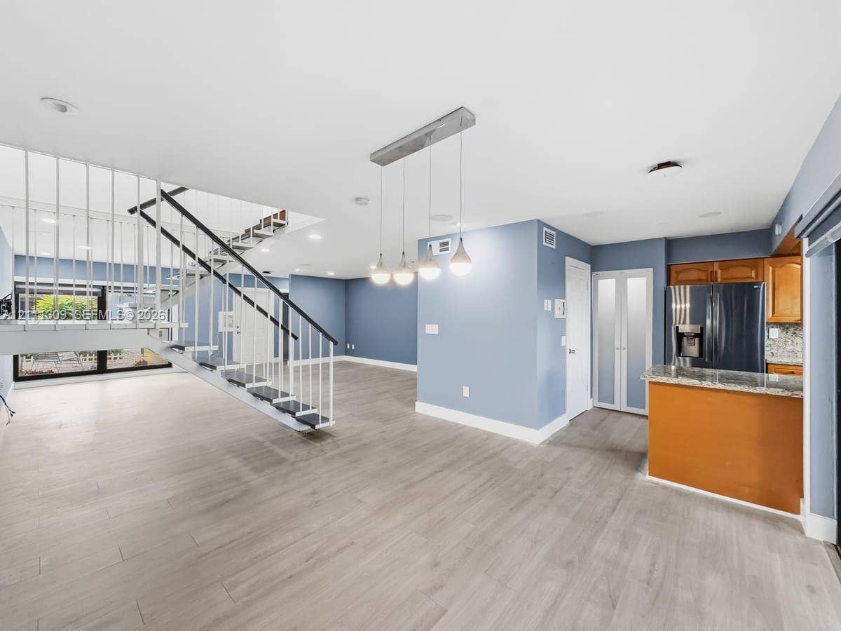 6518 Kendale Lakes Drive, #809, Miami, Miami, FL 33183 Open-concept interior featuring wood-finish flooring, a custom metal staircase with vertical railings, and a multi-pendant light fixture