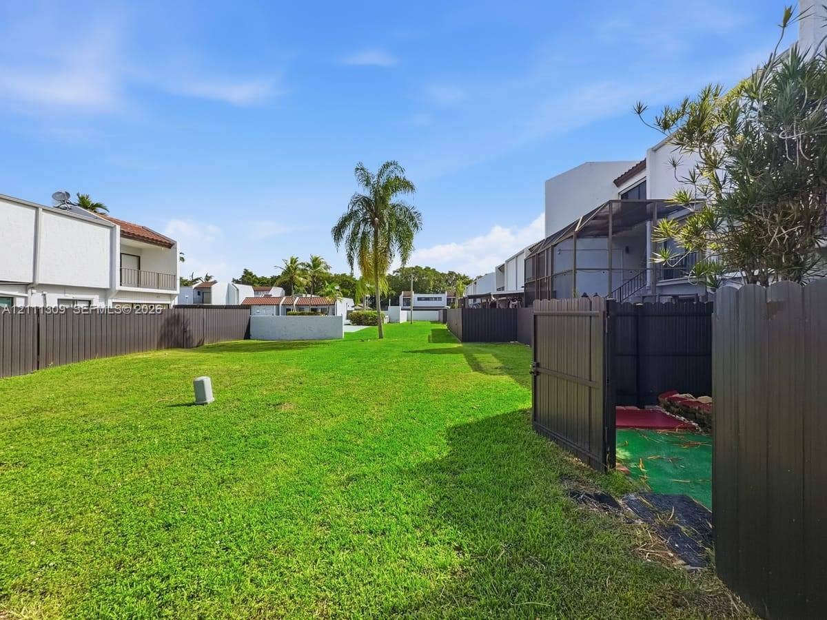 6518 Kendale Lakes Drive, #809, Miami, Miami, FL 33183 Expansive open green space featuring a manicured lawn, dark-toned privacy fencing, and a mature palm tree