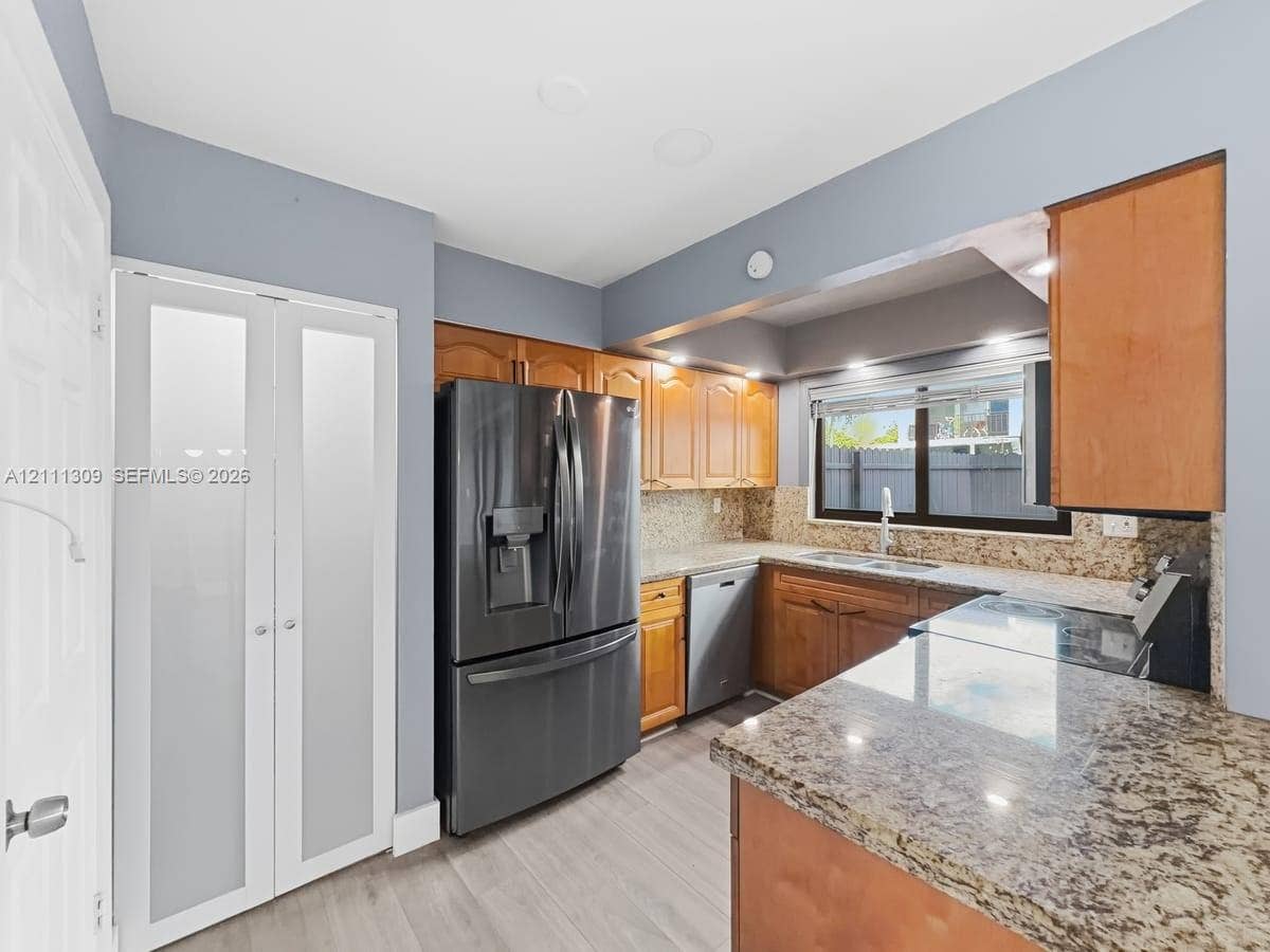 6518 Kendale Lakes Drive, #809, Miami, Miami, FL 33183 Kitchen featuring wood cabinetry, stone countertops, stainless steel appliances, a double-basin sink, and frosted-glass pantry doors