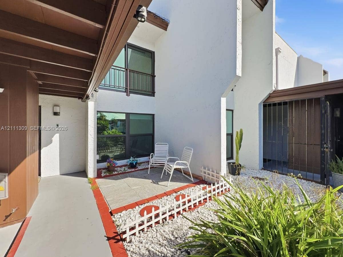 6518 Kendale Lakes Drive, #809, Miami, Miami, FL 33183 Stucco exterior facade featuring a covered entryway, private stone-paved patio, large windows, and a metal security gate