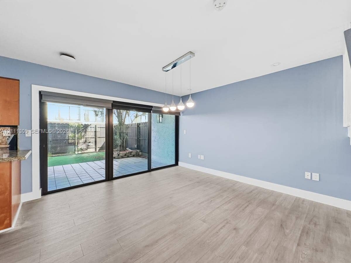 6518 Kendale Lakes Drive, #809, Miami, Miami, FL 33183 Expansive multi-panel sliding glass door, wood-finish flooring, linear four-light pendant fixture, and hardscaped patio