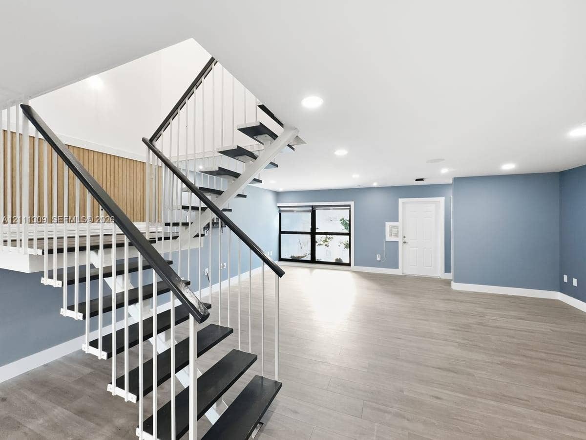 6518 Kendale Lakes Drive, #809, Miami, Miami, FL 33183 Open-concept interior featuring wood-finish flooring, a contemporary staircase with metal railings, a vertical wood slat accent wall, and recessed ceiling lighting
