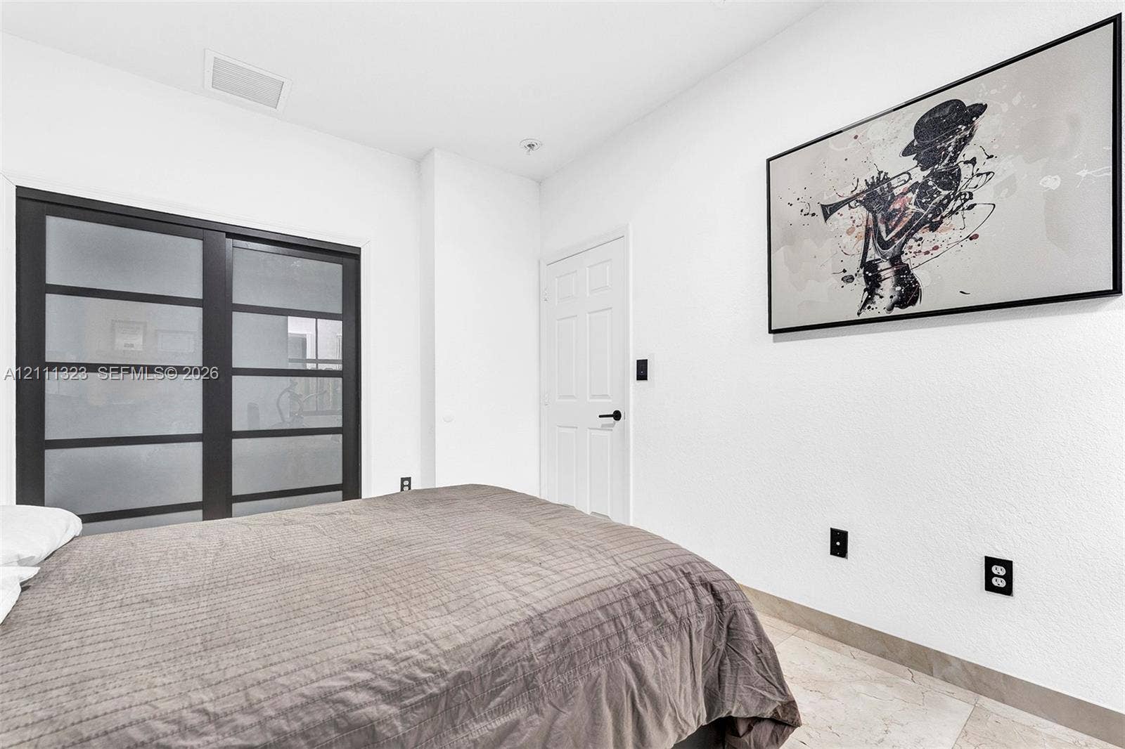 Sliding glass closet doors with dark frames and frosted panels, complemented by neutral tile flooring and a six-panel interior door