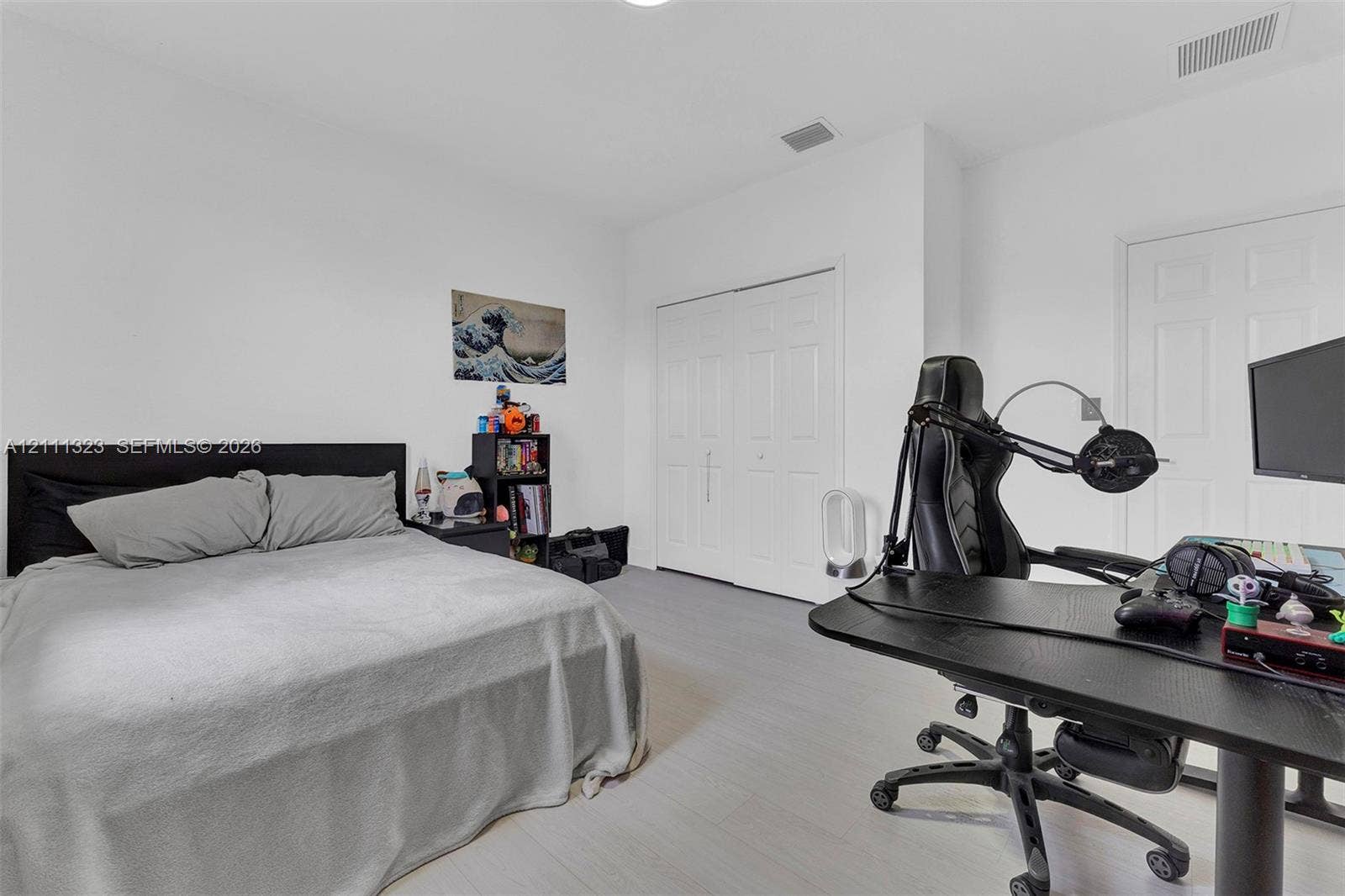 Neutral-toned interior space featuring wood-finish flooring, white walls, and a multi-panel closet with white doors