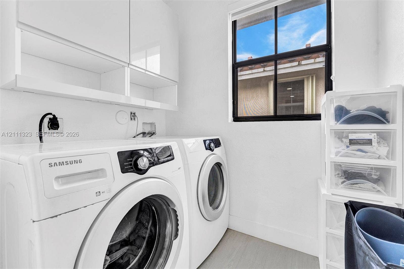 Utility space featuring white cabinetry, wood-finish flooring, and a window with black-framed panes