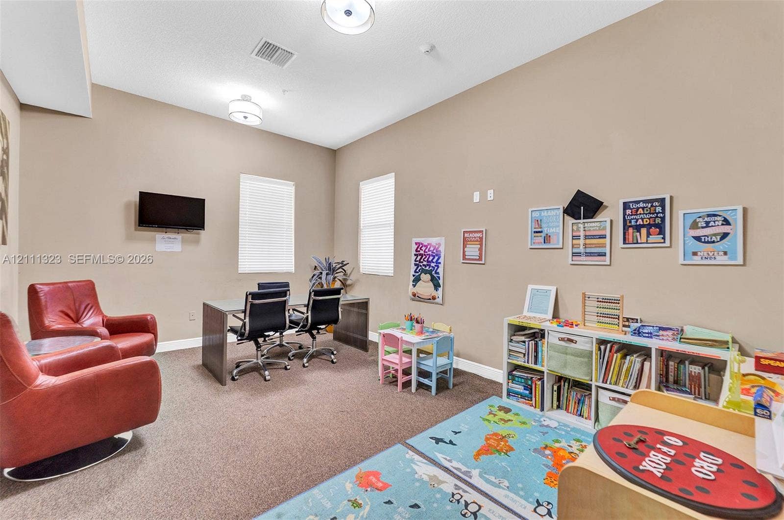 Multi-purpose room featuring high ceilings, two flush-mount light fixtures, neutral wall paint, and two windows with blinds