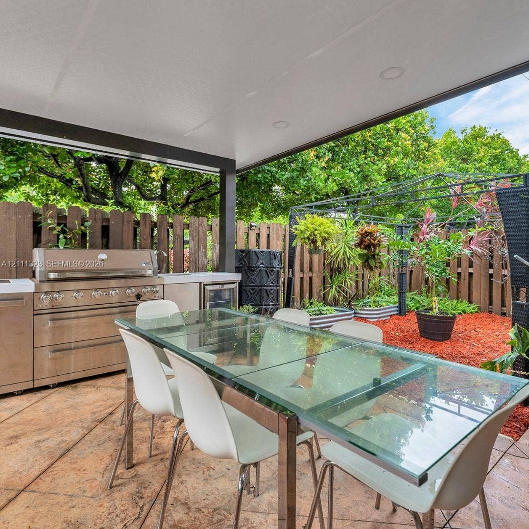 Covered patio featuring a concrete stamped floor, built-in stainless steel outdoor kitchen with integrated grill, and overhead recessed lighting
