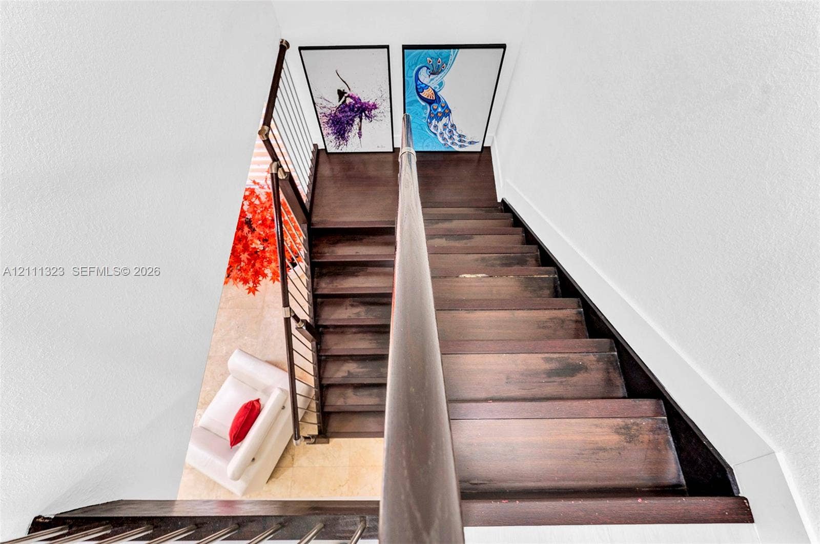 Staircase featuring dark-toned wood treads and a metal cable railing system with a continuous dark-toned handrail