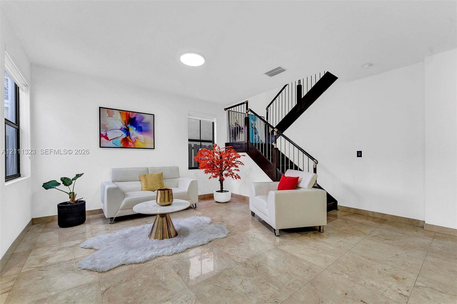 Open-concept area featuring polished tile flooring, a skylight, and a staircase with wooden treads and metal balusters