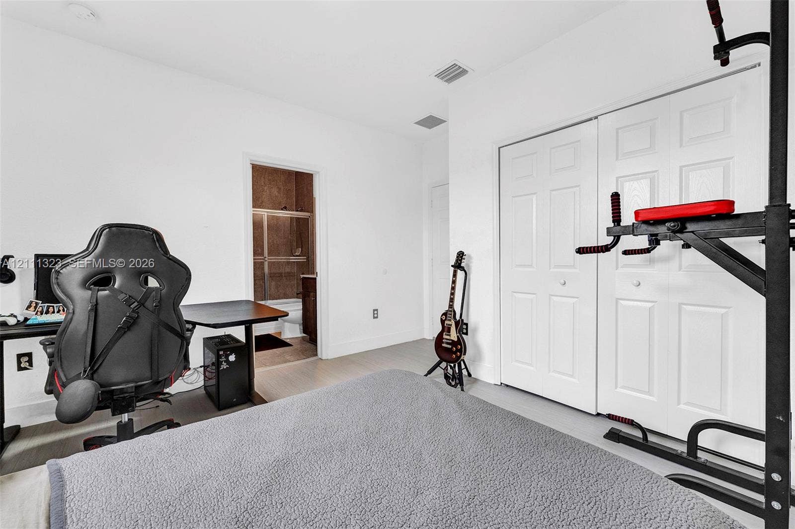 Room featuring white walls, neutral-toned flooring, and a double-door closet with paneled detailing