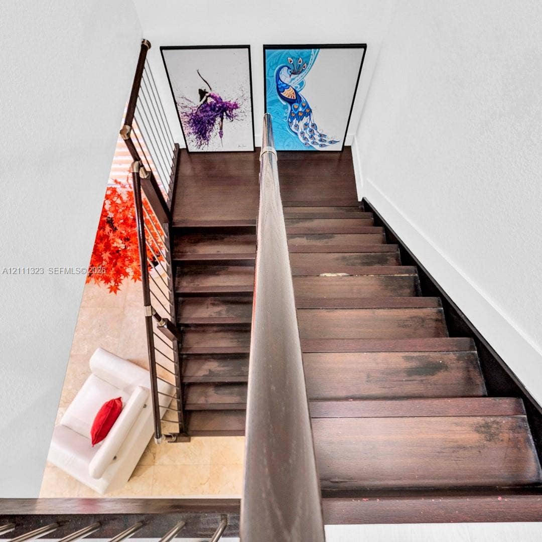 Staircase featuring dark-stained wooden treads, a matching handrail, and a metal tension-cable railing system