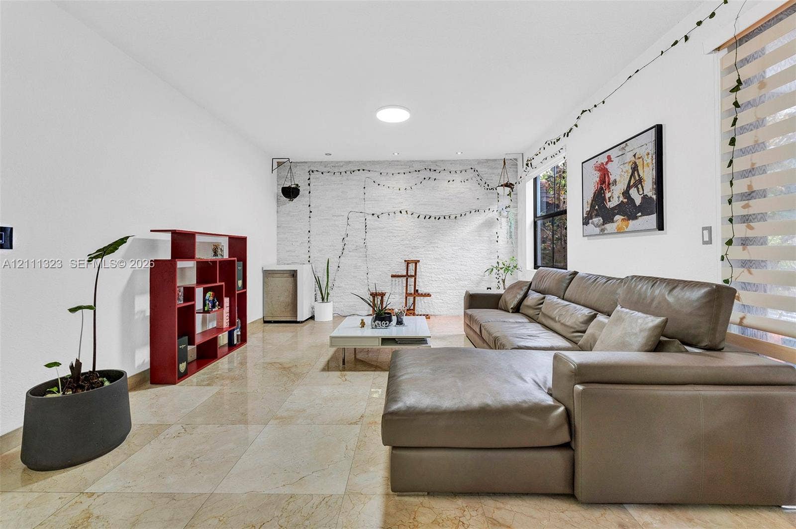 Large-format stone flooring, white-painted exposed brick wall, and a circular ceiling skylight