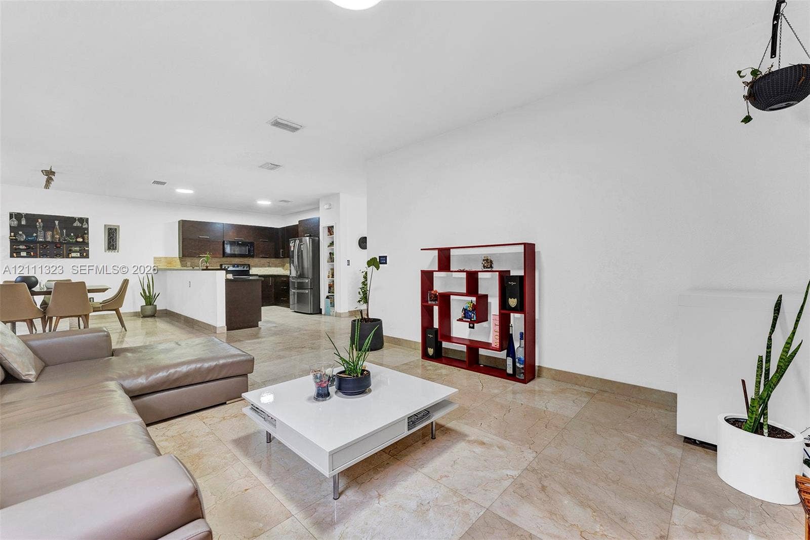 Open-concept interior featuring large-format tile flooring, recessed lighting, and a kitchen equipped with dark wood-finish cabinetry, stainless steel appliances, and a peninsula counter